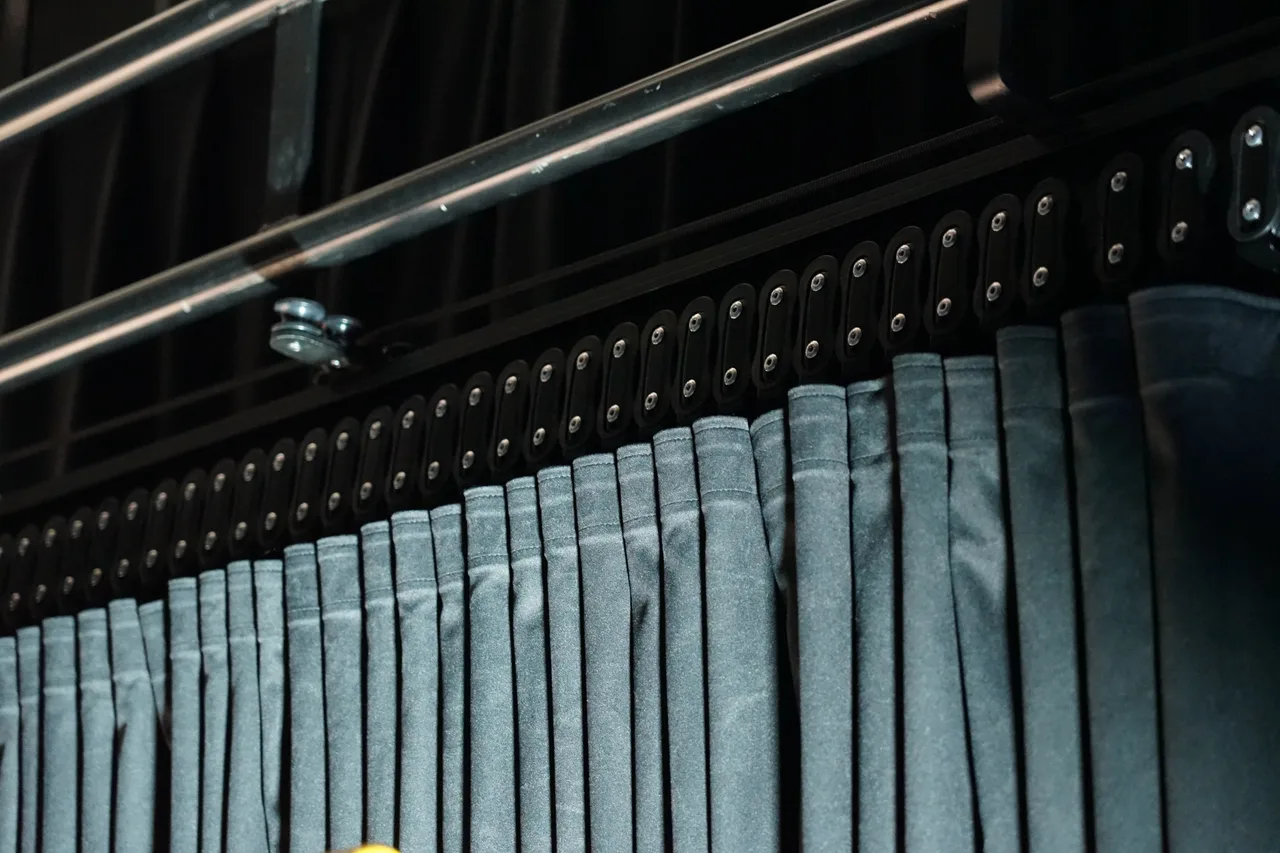 Track carriers supporting a pleated grey velvet drape