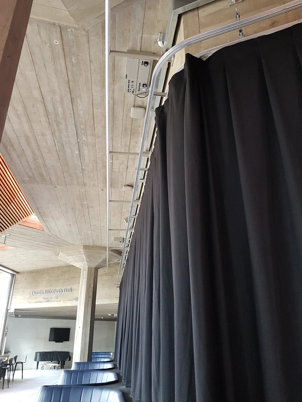 A curved ceiling-mounted 2Way curtain track carrying black drapes in a venue foyer