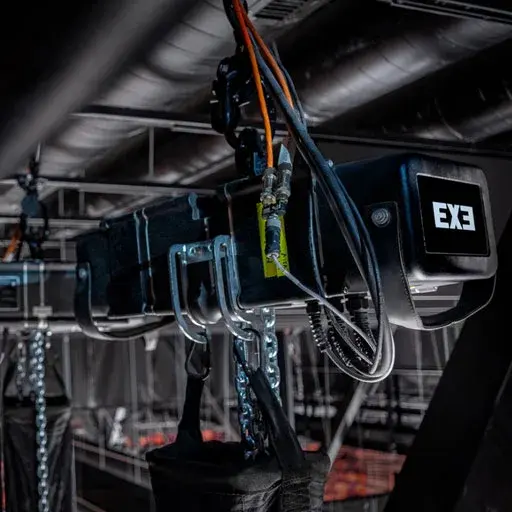Close-up of an EXE chain hoist with power cable and chain bag rigged to overhead steel.