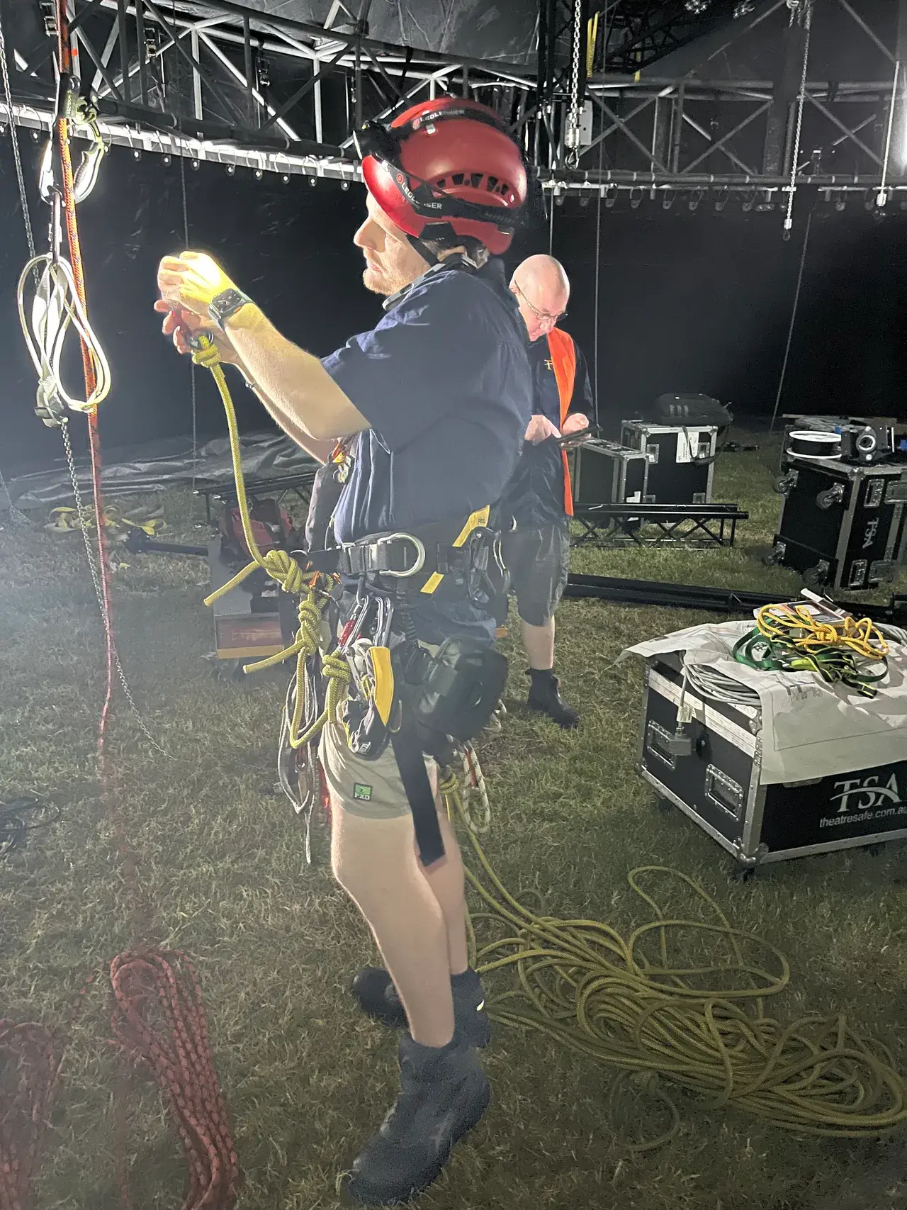 A TSA rigger in a rope-access harness with TSA road cases during Come Alive load-in