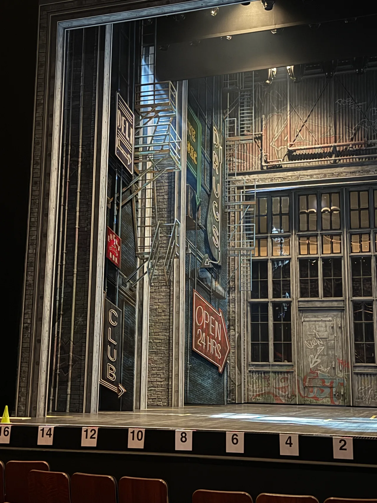 New York alleyway set with fire escapes and neon signage, from the auditorium