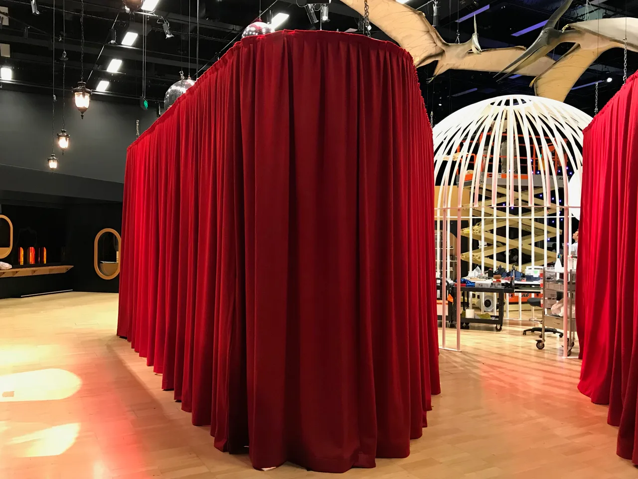 A freestanding red drape enclosure with a gathered pleated top under exhibition lighting at Melbourne Museum