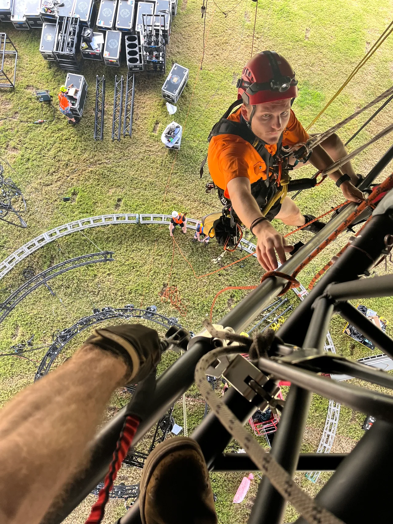 A rigger climbing a truss tower at the Come Alive outdoor site, shot from above