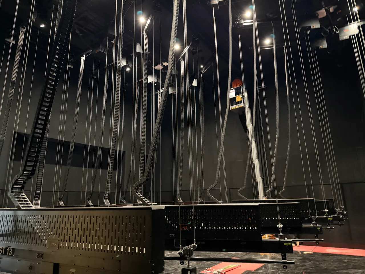 Automated fly lines and cable chains dropping from the grid above winch battens on Beetlejuice the Musical